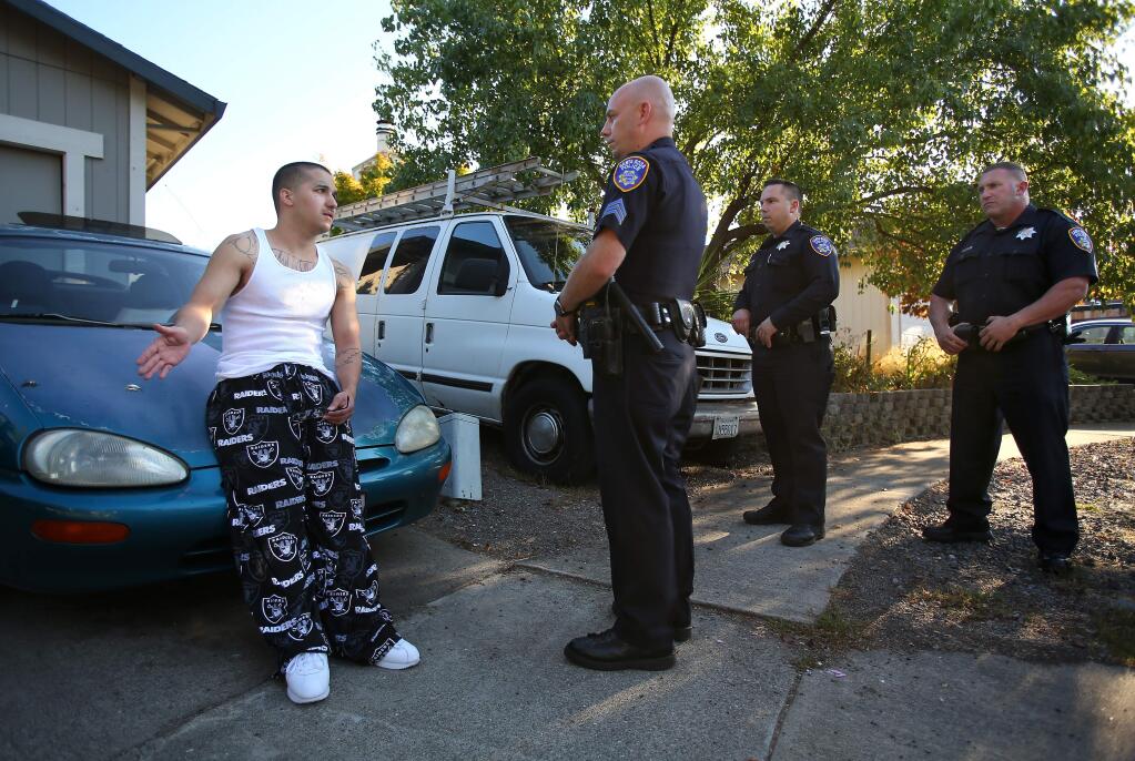 Santa Rosa Police gang unit Sgt. John Cregan, center, talks with felony parolee and known gang member, Chris McDaniel, left, as he and officers Jon Crespan and Robert Reynolds, conduct a parole search, in Santa Rosa on Thursday, Aug. 21, 2014. (CHRISTOPHER CHUNG/ PD FILE)