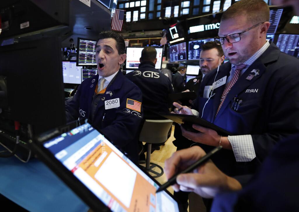 Specialist Peter Mazza, left, works with traders at his post on the floor of the New York Stock Exchange, Monday, Feb. 24, 2020. Stocks are opening sharply lower on Wall Street, pushing the Dow Jones Industrial Average down more than 700 points, as virus cases spread beyond China, threatening to disrupt the global economy. (AP Photo/Richard Drew)