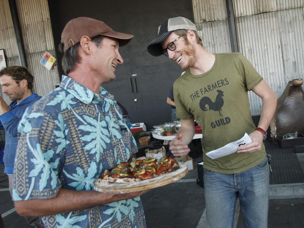 Evan Wiig, right, director of the Farmers Guild and the Free Farmers movement, and Cal Vanoni, left, Sprawling River Farm at Vanoni Ranch, chat before presenting pizza to the judges during a pizza making contest held at The Barlow, Thursday, August 28, 2014. (Crista Jeremiason / The Press Democrat)