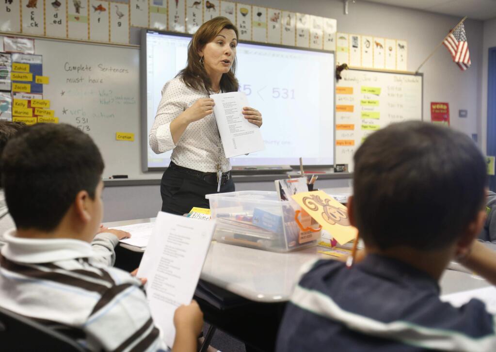 FILE - In this June 12, 2013 file photo second-grade teacher Vickie Boudouris goes over a an English work sheet with her students at the Cordova Villa Elementary School, in Rancho Cordova, Calif. The California State Board of Education is set to vote, Wednesday, May 8, 2019, on new guidance for teaching sex education in public schools. The guidance is not mandatory but it gives teachers ideas about teaching a wide range of health topics. (AP Photo/Rich Pedroncelli, File)