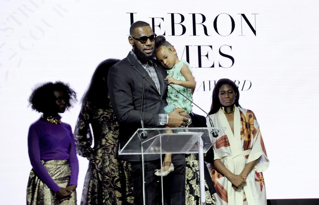 Basketball star LeBron James, holds his daughter Zhuri, as he accepts Harlem Fashion Row's ICON 360 Award for his contribution to fashion and philanthropy at the HFR fashion show and awards ceremony before the start of New York Fashion Week, Tuesday, Sept. 4, 2018. (AP Photo/Diane Bondareff)
