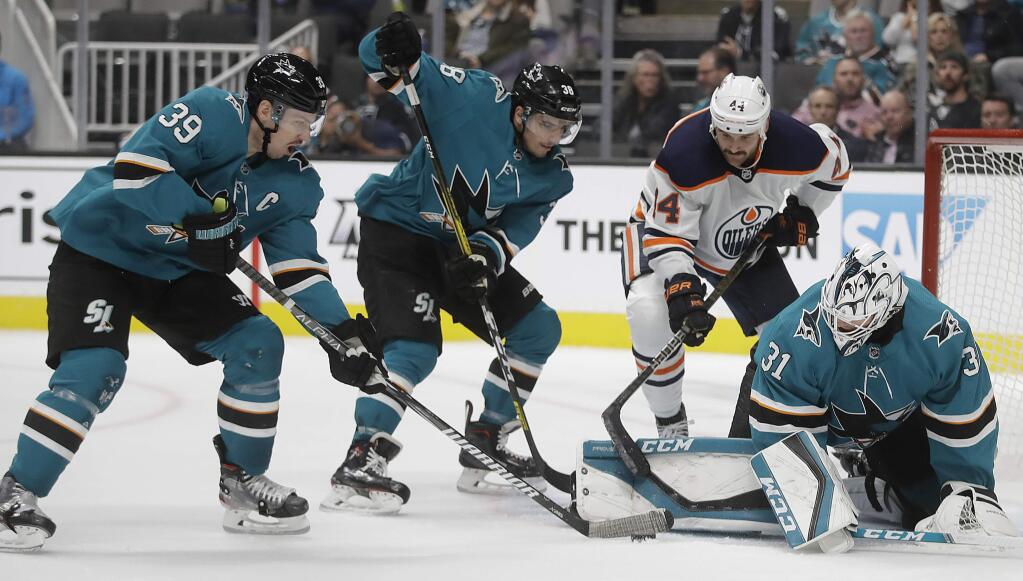 The San Jose Sharks' Logan Couture (39), Mario Ferraro (38) and goalie Martin Jones, right, defend against a shot from Edmonton Oilers' Zack Kassian, second from right, during the second period Tuesday, Nov. 19, 2019, in San Jose. (AP Photo/Ben Margot)