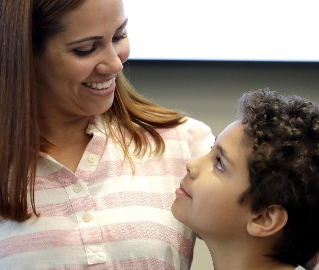 Lidia Karine Souza and her son Diogo De Olivera Filho smile at each other at the Mayer Brown law firm during a news conference shortly after Diogo was reunited with his mother Thursday, June 28, 2018, in Chicago. Federal judge Manish Shah earlier today ordered the immediate release from detention of the 9-year-old Diogo who was separated from his mother at the U.S.-Mexico border in May. (AP Photo/Charles Rex Arbogast)
