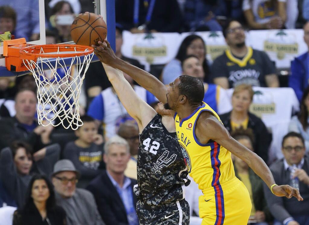 Golden State Warriors forward Kevin Durant blocks a shot attempt by the San Antonio Spurs' Davis Bertans during their game in Oakland on Thursday, March 8, 2018. (Christopher Chung/ The Press Democrat)