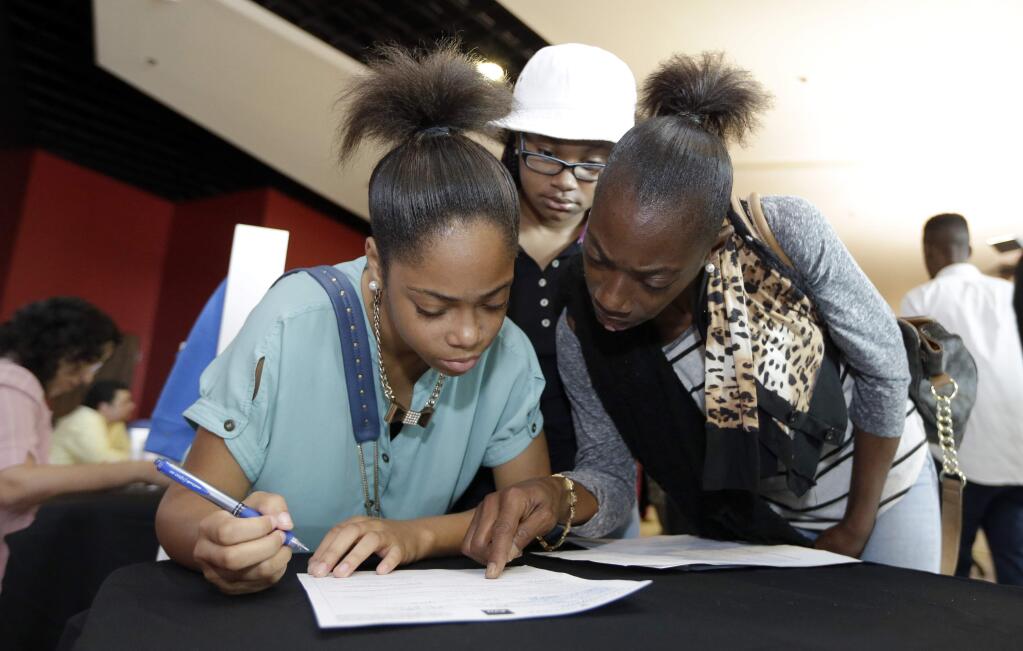 In this June 10, 2015, photo, Lashrundra Wilfork, right, helps her daughter, Nala Wilfork, fill out a job application at a job fair in Sunrise, Fla. The Labor Department releases job openings and labor turnover survey for June on Wednesday, Aug. 12, 2015. (AP Photo/Alan Diaz)