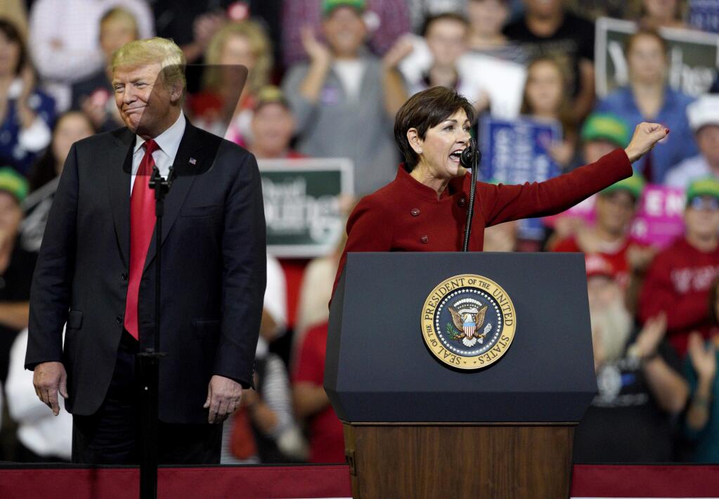 President Donald Trump reacts to words spoken by Iowa Gov. Kim Reynolds, during a Make America Great Again rally at the Mid-America Center in Council Bluffs, Iowa, Tuesday, Oct. 9, 2018. (AP Photo/Nati Harnik)