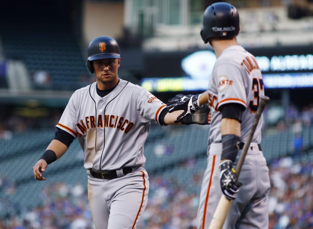 The San Francisco Giants' Joe Panik, left, is congratulated by on-deck batter Kelby Tomlinson after Panik and Hunter Pence scored on a single by Austin Slater off Colorado Rockies starting pitcher Kyle Freeland during the first inning Wednesday, Sept. 6, 2017, in Denver. (AP Photo/David Zalubowski)
