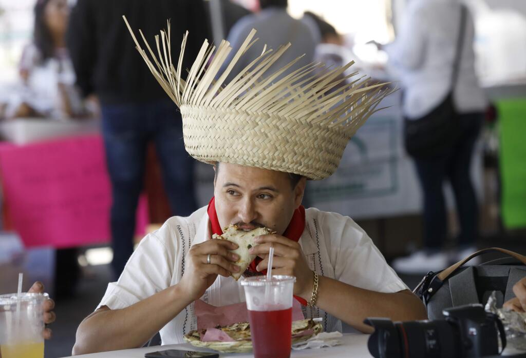 Sal Gonzalez eats a tlayuda and wears a Oaxacan style hat during the Guelaguetza Tierra del Sol at the Luther Burbank Center for the Arts in Santa Rosa on Sunday, July 15, 2018. (Beth Schlanker/ The Press Democrat)