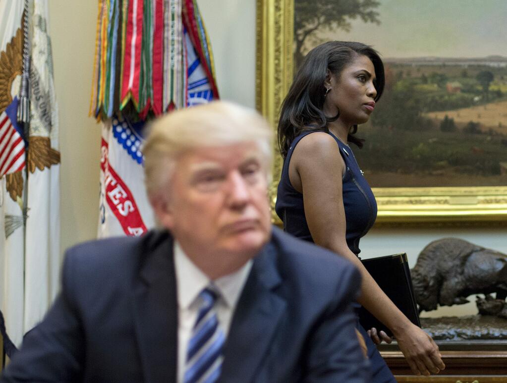 FILE - In this March 12, 2017 file photo, White House Director of communications for the Office of Public Liaison Omarosa Manigault, right, walks past President Donald Trump during a meeting on healthcare in the Roosevelt Room of the White House in Washington. Manigault Newman, who was fired in December, released a new book 'Unhinged,' about her time in the White House. (AP Photo/Pablo Martinez Monsivais, File)