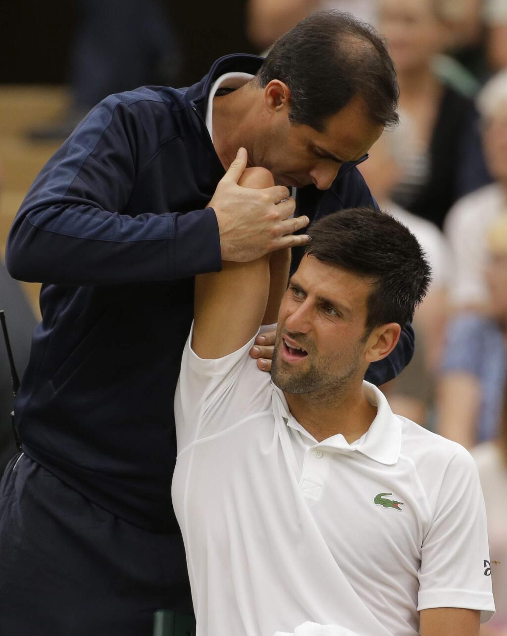 FILE - This is a Tuesday, July 11, 2017 file photo of Serbia's Novak Djokovic as he receives treatment from a trainer during a break in his Men's Singles Match against Adrian Mannarino of France on day eight at the Wimbledon Tennis Championships in London. Novak Djokovic will miss the rest of this season because of an injured right elbow. The 12-time major champion will skip the U.S. Open. That ends his streak of playing in 51 consecutive Grand Slam tournaments. (AP Photo/Alastair Grant/File)
