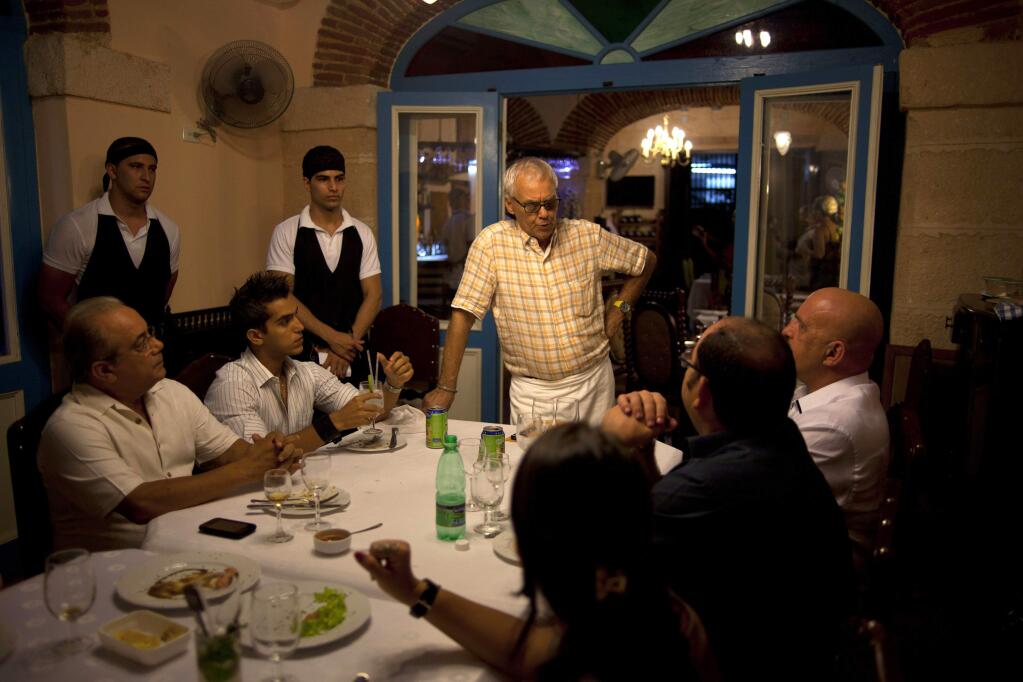Tomas Erasmo Hernande with his customers in at Mama nnes, a private restaurant in Old Havana. Cuba is freezing new licenses for private restaurants amid complaints that competition is huring government-owned restaurants. (RAMON ESPINOSA / Associated Press, 2012)