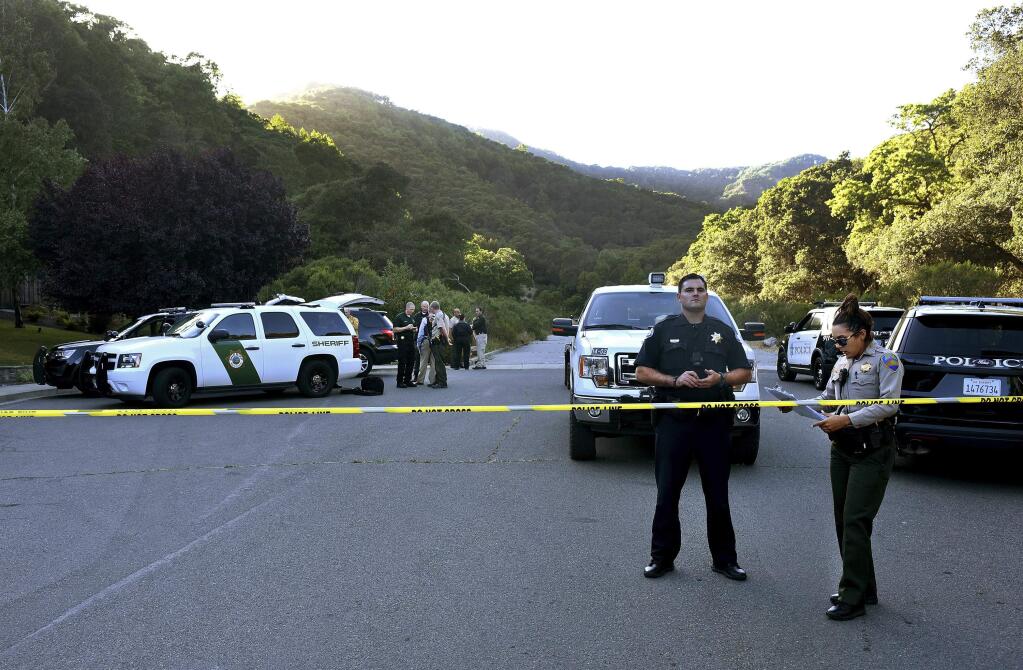 In this photo taken Wednesday, May 25, 2016, Marin County Sheriff and Novato police members gather at a command post to form a manhunt following at attack on two students. Attackers shot two students Wednesday near the San Francisco Bay Area high school, killing one and sending another to a hospital in an incident that prompted the closing of the campus to students. (Robert Tong/Marin Independent Journal via AP)