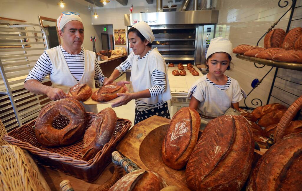 photos by John Burgess / The Press DemocratNas Salamati, left, runs Goguette Bakery on Montgomery Drive in Santa Rosa with help from his wife, nutritionist Nagine Shariat, and their 11-year-old daughter, Soraya. Below, Nas removes a 3-foot long loaf of pain de partage (bread to share), one of a variety of breads he bakes, out of the oven.