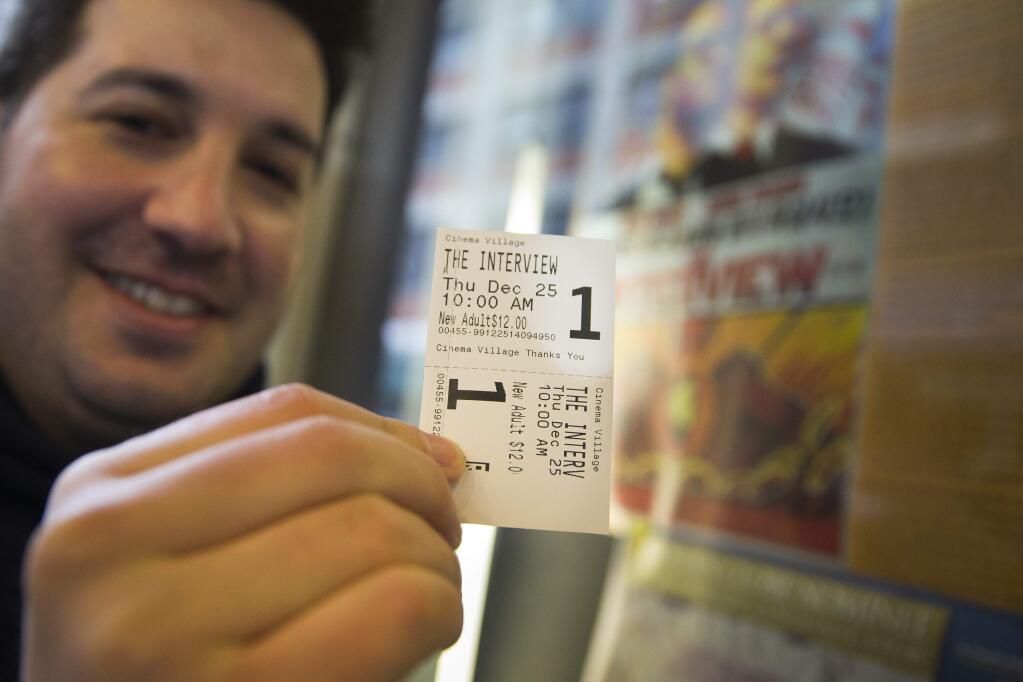FILE - In this Dec. 25, 2014 file photo, Derek Karpel holds his ticket to a screening of 'The Interview' at Cinema Village movie theater, in New York. The film raked in just over $1 million in ticket sales from 331 locations for an impressive $3,142 per theater average, according to distributor Sony Pictures. (AP Photo/John Minchillo, File)