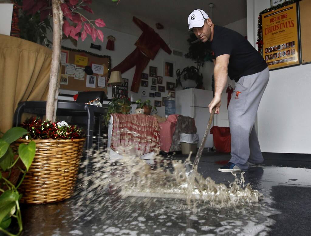 FILE - In this Jan. 5, 2016, file photo, Chris Lene sweeps water out of one of the businesses in the building he owns that was flooded by rainwater in Sacramento, Calif. Climate change is making stronger El Ninos, which change weather worldwide and heat up an already warming planet, according a study in Proceedings of the National Academy of Sciences on Monday, Oct. 21, 2019. (AP Photo/Rich Pedroncelli, File)