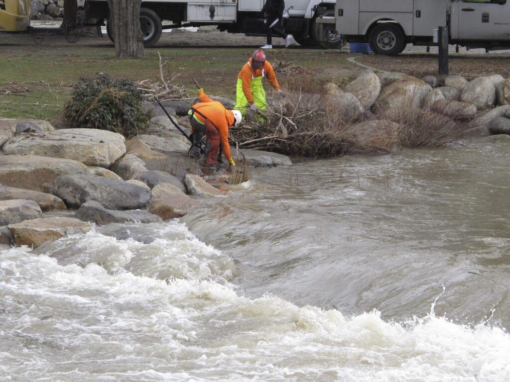 City crews clear tree branches and debris from the Truckee River in downtown Reno, Nev., Tuesday, Jan. 10, 2017, after flooding sent water over the banks and caused to close all downtown bridges the day before. (AP Photo/Scott Sonner)