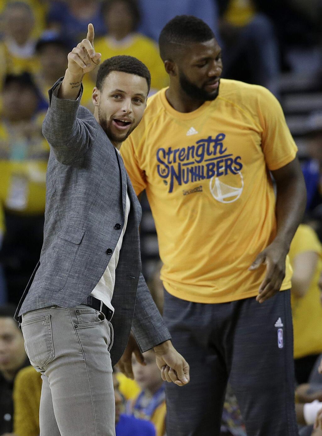 Golden State Warriors guard Stephen Curry, left, gestures next to center Festus Ezeli from the bench during the first half in Game 2 of a second-round NBA basketball playoff series against the Portland Trail Blazers in Oakland, Calif., Tuesday, May 3, 2016. (AP Photo/Marcio Jose Sanchez)