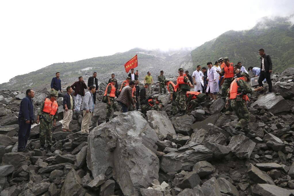 In this photo released by China's Xinhua News Agency, emergency personnel work at the site of a landslide in Xinmo village in Maoxian County in southwestern China's Sichuan Province, Saturday, June 24, 2017. Around 100 people are feared buried by a landslide that unleashed huge rocks and a mass of earth that crashed into their homes Saturday, a county government said. (He Qinghai/Xinhua via AP)