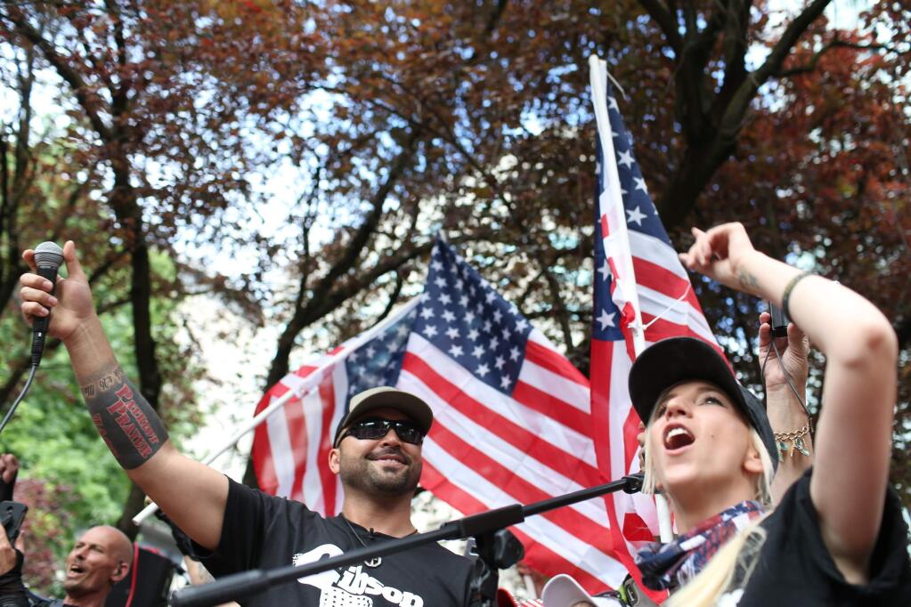 FILE--In this June 30, 2018, file photo, Joey Gibson, left, leader of Patriot Prayer, heads the group's rally in Portland, Ore. Portland is bracing for what could be another round of violent clashes Saturday, Aug. 4, 2018, between a right-wing group holding a rally here and self-described anti-fascist counter-protesters who have pledged to keep Patriot Prayer and other affiliated groups out of this ultra-liberal city. (Mark Graves/The Oregonian via AP, file)