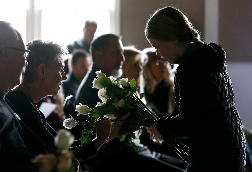 Charlyse Lloyd, 9, right, gives a white rose to Maryann Lyon and each attendee during a memorial service for Jennifer Golick, Christine Loeber, Jennifer Gonzales Shushereba, and her unborn baby, who were victims of a shooting last year at the Pathway Home veterans treatment program, in Yountville, California, on Saturday, March 9, 2019. (Alvin Jornada / The Press Democrat)