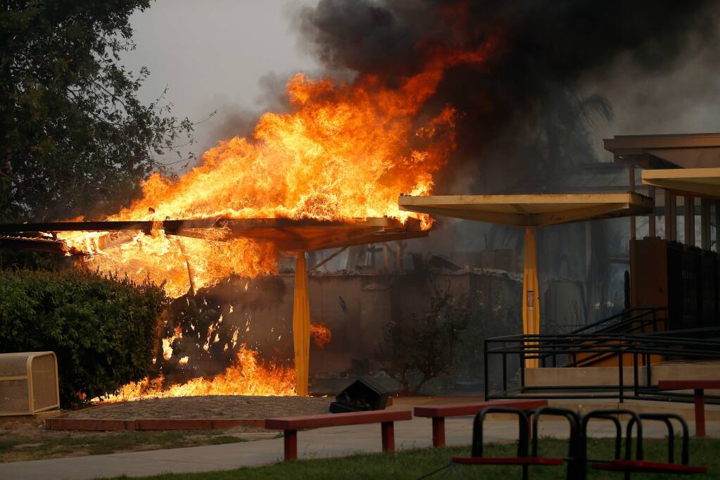 An awning blazes beside the locker area on the campus of Cardinal Newman High School after the Tubbs Fire burned through north Santa Rosa, California on Monday, October 9, 2017. (Alvin Jornada / The Press Democrat)