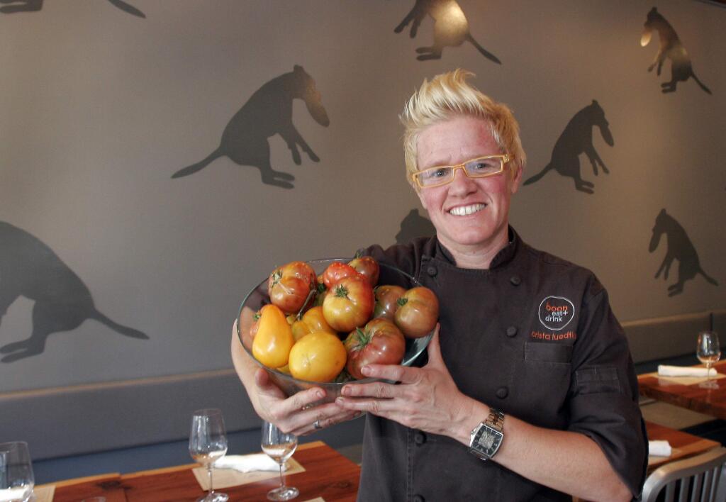 Boon Eat + Drink's chef/owner Crista Luedtke holds tomatoes from her garden in 2010 in her restaurant dining room, which features silhouettes of her dog Boon on the walls. (Press Democrat photo)