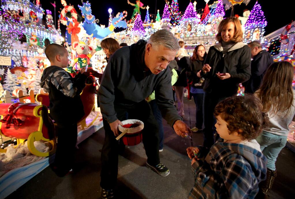 Scott Weaver, center, passes out candy canes a day after his Rohnert Park home was featured on ABC's 'The Great Christmas Light Fight', Tuesday, December 9, 2014. Weaver won the competition that came with a $50,000 prize. (Crista Jeremiason / The Press Democrat)