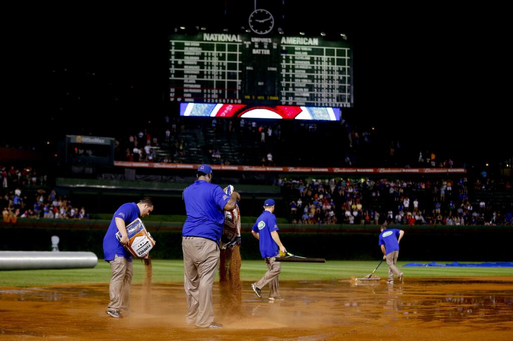 The grounds crew works on the field after a heavy rain soaked Wrigley Field during the fifth inning of a baseball game between the San Francisco Giants and the Chicago Cubs on Tuesday, Aug. 19, 2014, in Chicago. (AP Photo/Jeff Haynes)