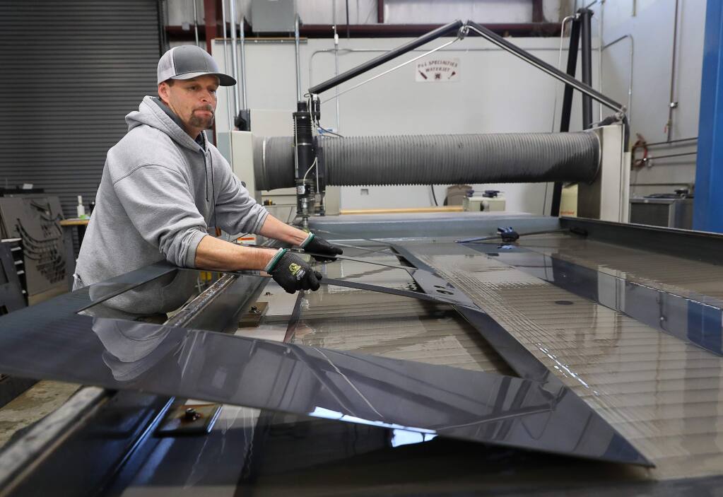 Dustin Holbrook lifts a steel frame for a custom cut door from the water jet machine at P&L Specialties, in Santa Rosa on Thursday, January 3, 2019. (Christopher Chung/ The Press Democrat)