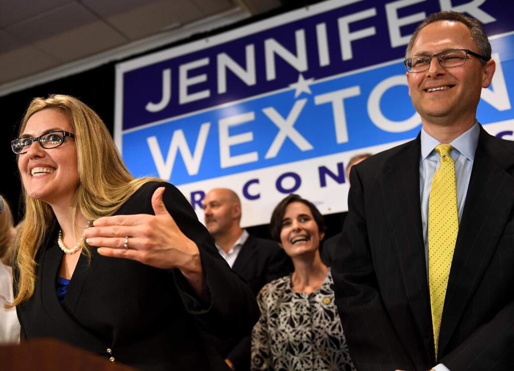 Democrat Jennifer Wexton talks to supporters flanked by her husband, Andrew, Tuesday in Dulles, Va. Wexton beat incumbent Barbara Comstock in Virginia's 10th congressional district. MUST CREDIT: Washington Post photo by Katherine Frey