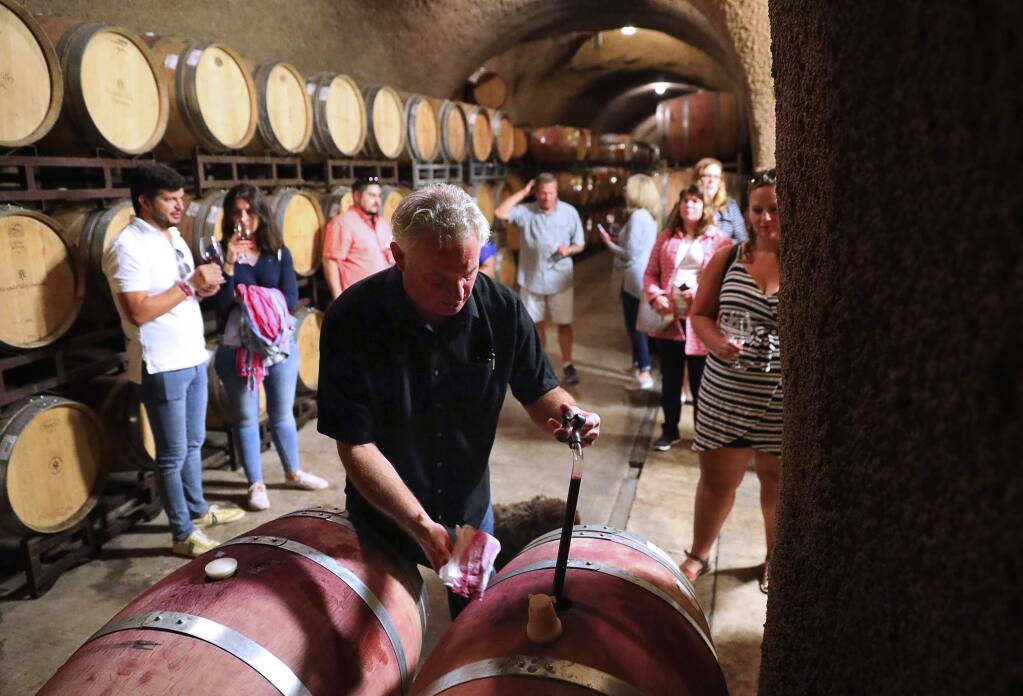 Tim Yeakel, tasting room lead, pulls a sample of wine from a barrel for a group of visitors in the Alexander Valley Vineyards cave, in Healdsburg on Tuesday, August 21, 2018. (Christopher Chung/ The Press Democrat)