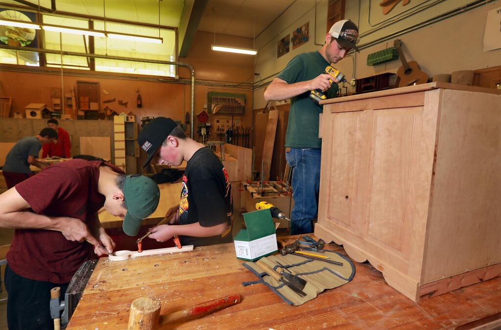 Justin Schaap, right, puts the finishing touches on a cherry gun cabinet base while Jordan Pennington carves a spoon in the woodshop class at El Molino High School. The dance and woodshop classes at the Forestville school are facing cuts due to budget deficits. (photo by John Burgess/The Press Democrat)