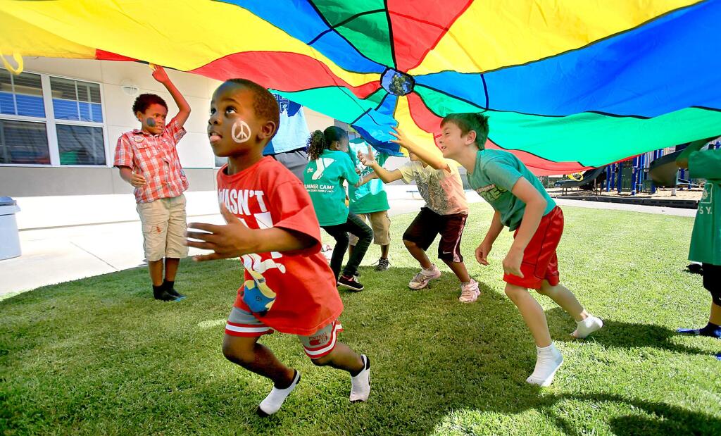 Six year-old's Alton Broussard, left and Camdan Brasil play cat and mouse under a parachute, Thursday Aug. 13, 2015 at a YMCA camp at Jack London Elementary School in Santa Rosa. As area school's start their fall semesters, summer camps are winding down. (Kent Porter / Press Democrat) 2015