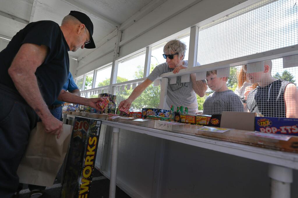Joe Phaby, left, helps customer Sam Dakin, accompanied by his son Jolyon Dakin and nephew Cooper Jeffree, at the fireworks stand operated by VFW Post 3919, at the Fiesta Shopping Center in Sebastopol on Friday, June 28, 2019. (Christopher Chung/ The Press Democrat)