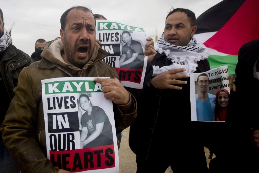 Palestinian demonstrators hold portraits of Kayla Mueller, a 26-year-old American who died while being held hostage by the Islamic State group, during a weekly demonstration against Israel's separation barrier in the West Bank village of Bilin near Ramallah, Friday, Feb. 13, 2015. Her death was confirmed this week by her family and the U.S. government, but how she died remained unclear. (AP Photo/Majdi Mohammed)