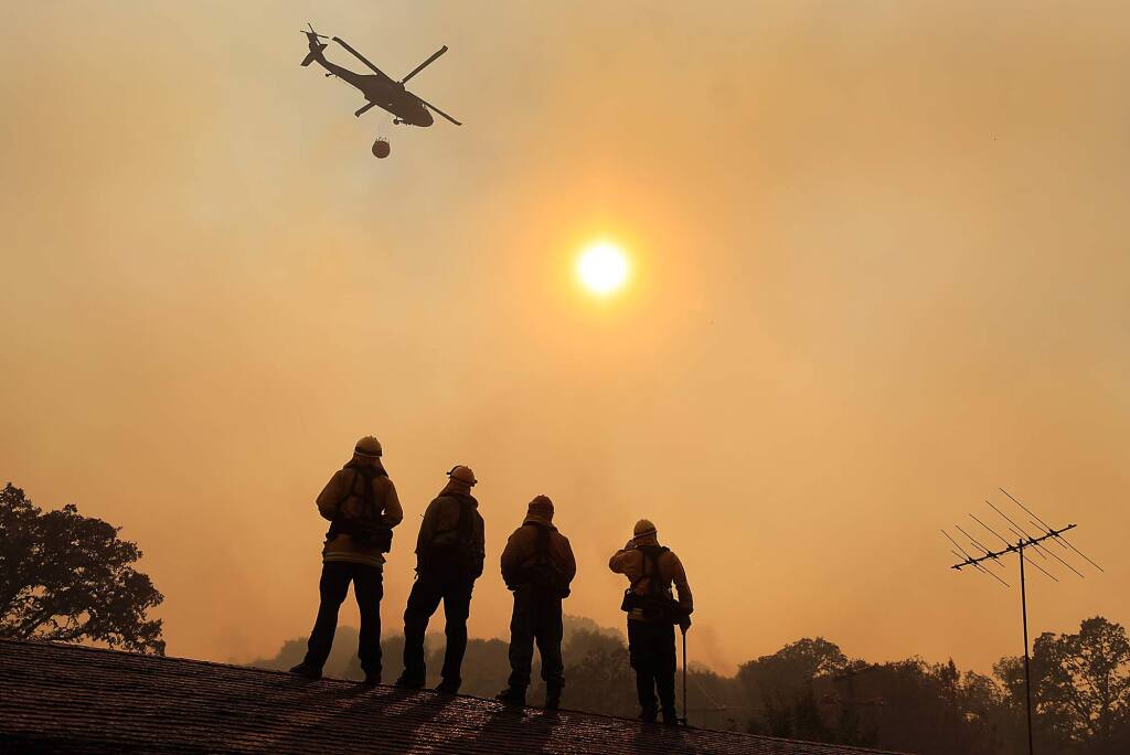 Firefighters stand watch on a roof during the River fire on Scotts Valley Road near Lakeport on Thursday, Aug. 2, 2018. (KENT PORTER/ PD)