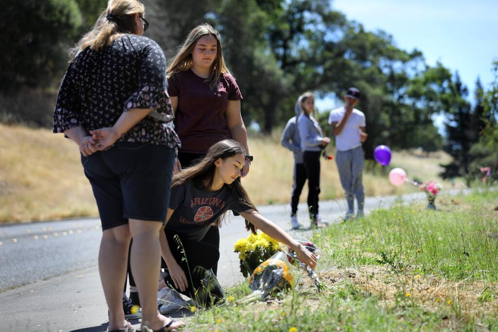 Rachel Fong, 16, joined by her friend Abigail Rasore, 15, rear, and Abigail's mother Jennifer Rasore, places a bouquet of flowers on the ground as they remember their 16-year-old friend who died in a car accident at the corner of Thomas Lake Harris Drive and Skyfarm Drive in Santa Rosa on Monday, July 1, 2019. Click through to see photos from the most-read stories of 2019. (BETH SCHLANKER/ PD)