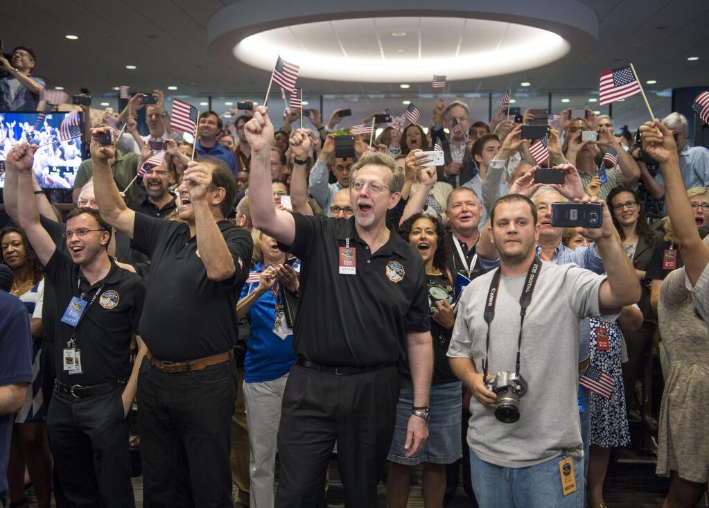 Jim Green, NASA Planetary Science Division director, center, and other New Horizons team members count down to the spacecraft's closest approach to Pluto, Tuesday, July 14, 2015 at the Johns Hopkins University Applied Physics Laboratory (APL) in Laurel, Maryland. The moment of closest approach for the New Horizons spacecraft came around 7:49 a.m. EDT Tuesday, culminating an epic journey from planet Earth that spanned an incredible 3 billion miles and 9O years. (Bill Ingalls/NASA via AP)