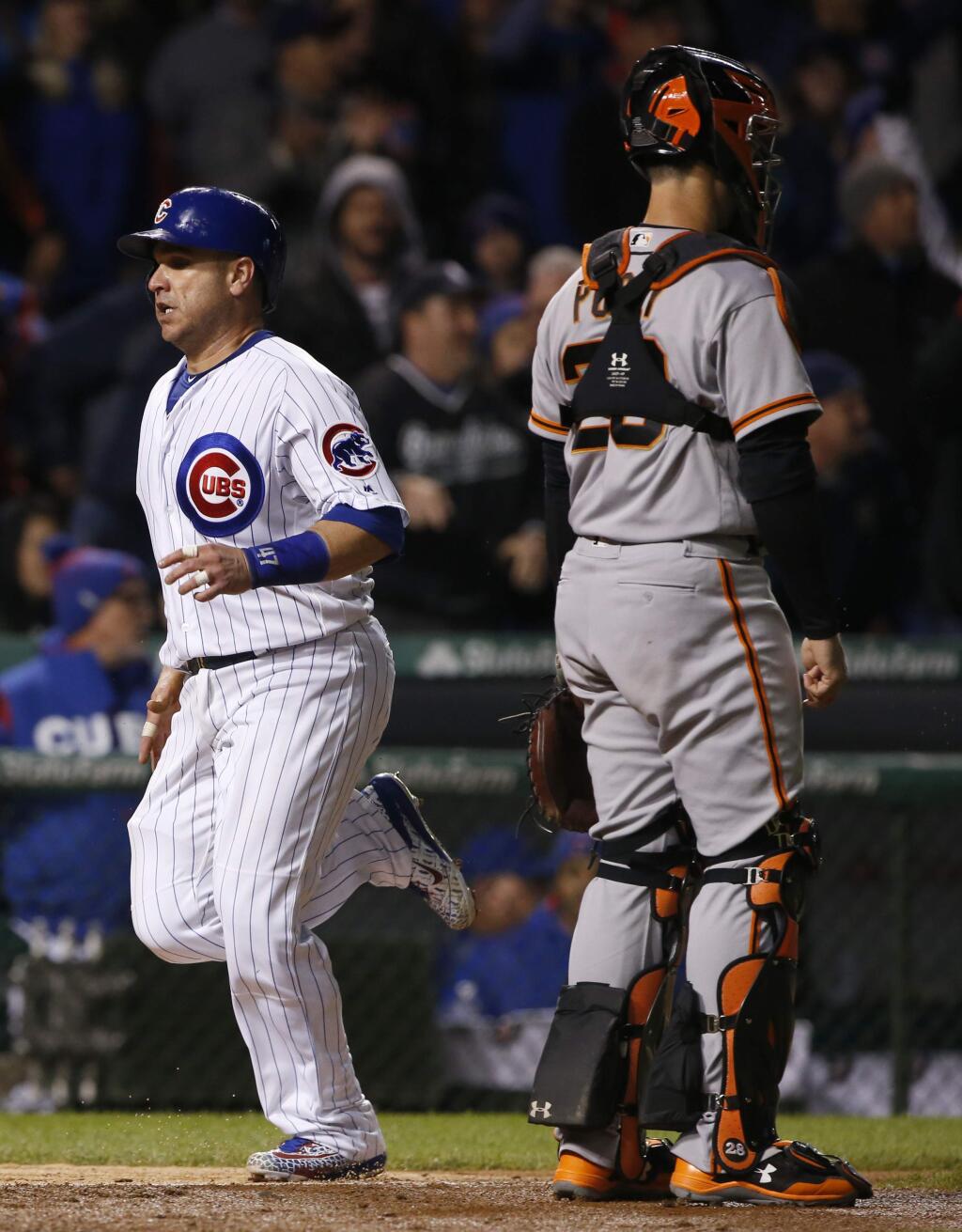 Chicago Cubs' Miguel Montero, left, scores on a sacrifice bunt by Javier Baez as San Francisco Giants catcher Buster Posey waits for the ball during the seventh inning of a baseball game, Wednesday, May 24, 2017, in Chicago. (AP Photo/Nam Y. Huh)