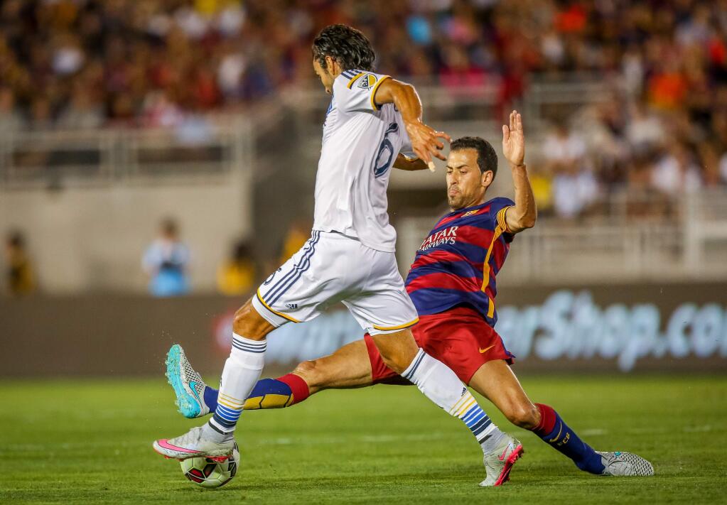 FC Barcelona's Sergio Busquets tries to gain control over the ball from LA Galaxy's Baggio Hasidic during Tuesday's soccer match at the Rose Bowl in Pasadena, July 21, 2015. (Doug Benc/AP Images for International Champions Cup)