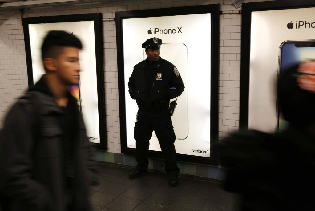 A police officer patrols in the passageway connecting New York City's Port Authority bus terminal and the Times Square subway station Tuesday, Dec. 12, 2017, near the site of Monday's explosion. Commuters returning to New York City's subway system on Tuesday were met with heightened security a day after a would-be suicide bomber's rush-hour blast failed to cause the bloodshed he intended. (AP Photo/Seth Wenig)