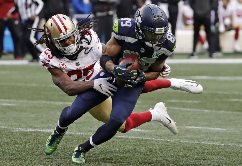 San Francisco 49ers cornerback Richard Sherman, left, tries to tackle Seattle Seahawks wide receiver Doug Baldwin during the second half, Sunday, Dec. 2, 2018, in Seattle. Baldwin managed to break the tackle and gain yardage. (AP Photo/Elaine Thompson)