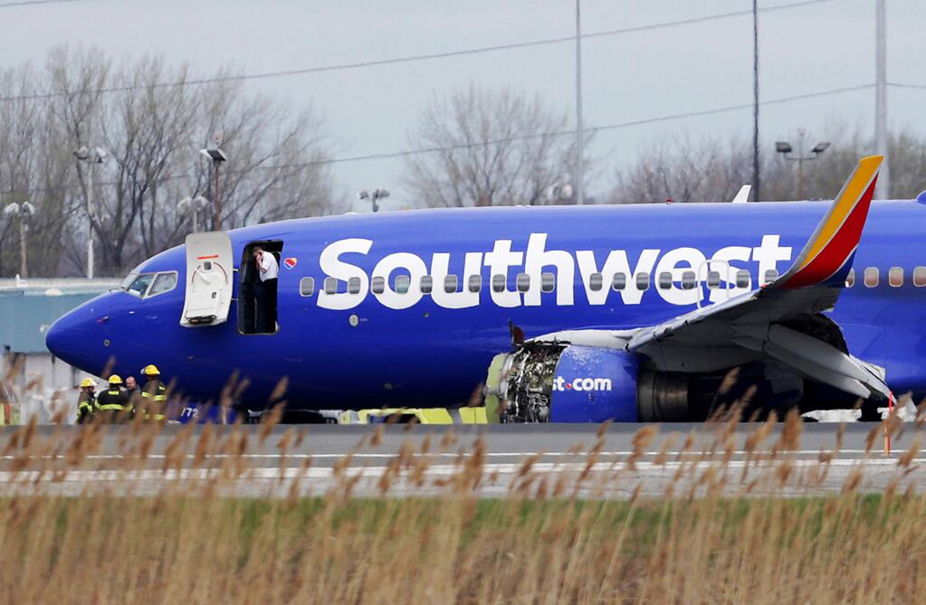 FILE- In this April 17, 2018, file photo a Southwest Airlines plane sits on the runway at the Philadelphia International Airport after it made an emergency landing in Philadelphia. In new accounts released Wednesday, Nov. 14, into the April accident, the flight attendants described being unable to bring the woman back in the plane until two male passengers stepped in to help. The flight attendants told investigators at least one of the men put his arm out of the window and wrapped it around the woman's shoulder to help pull her back in. (David Maialetti/The Philadelphia Inquirer via AP)