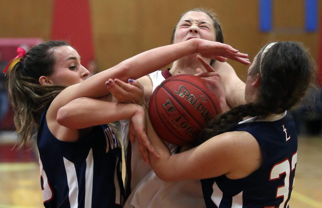Cardinal Newman's Kylie Kiech is fouled as she drives to the basket between Justin-Siena's Haley Weaver, left, and Catherine Cronwall, right, during the game held at Cardinal Newman High School, Saturday, February 28, 2015. (Crista Jeremiason / The Press Democrat)
