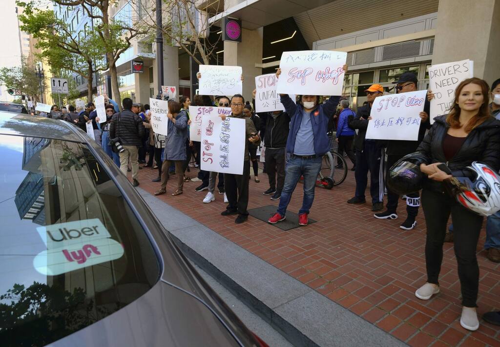 FILE - In this May 8, 2019,, file photo, Uber and Lyft drivers carry signs during a demonstration outside of Uber headquarters in San Francisco. Companies like Uber and Lyft helped create the so-called gig economy. Legislation pending in the Assembly could set a clearer standard for who, exactly, is an independent contractor with a 'gig' and who has the rights of a full-fledged employee. Backed by labor unions, the bill, AB5, could expand rights and benefits to workers now labeled independent contractors, in turn upending some industries. (AP Photo/Eric Risberg, File)