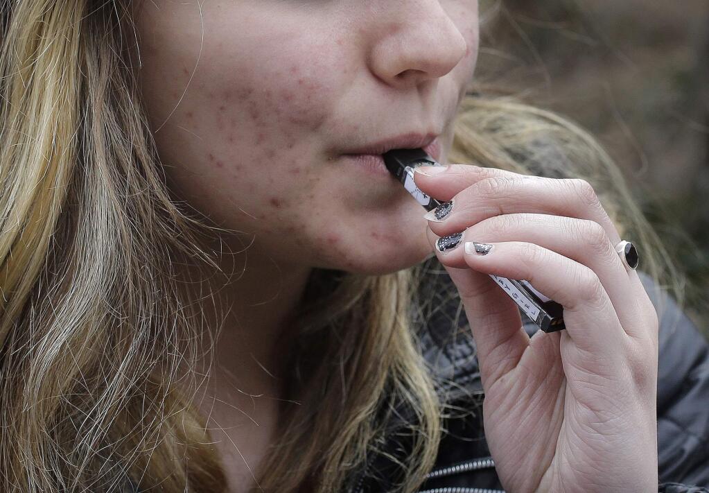FILE - In this April 11, 2018, file photo, an unidentified 15-year-old high school student uses a vaping device near the school's campus in Cambridge, Mass. (AP Photo/Steven Senne, File)