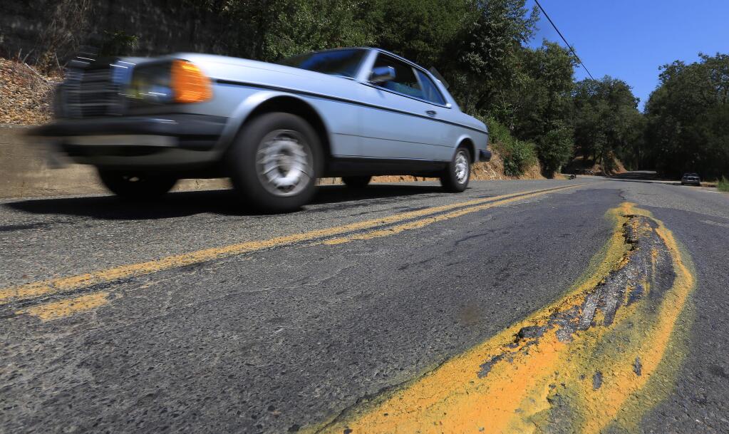A damaged and filled pothole is marked as a hazard for drivers along Westside Road near MacMurray Ranch Friday Sept. 5, 2014. The oft traveled road used by locals and tourists alike has been repaved closer to Healdsburg, but a large stretch of the road is carpeted with patched and un-patched potholes. (Kent Porter / Press Democrat) 2014