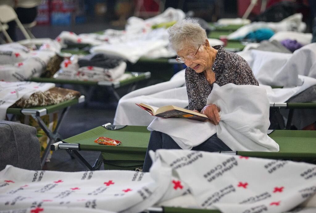 Joy Ryan, who evacuated her home in Oakmont, passes the time Tuesday by reading a book at the Red Cross shelter at the Sonoma County Fairgrounds. (JOHN BURGESS / The Press Democrat)