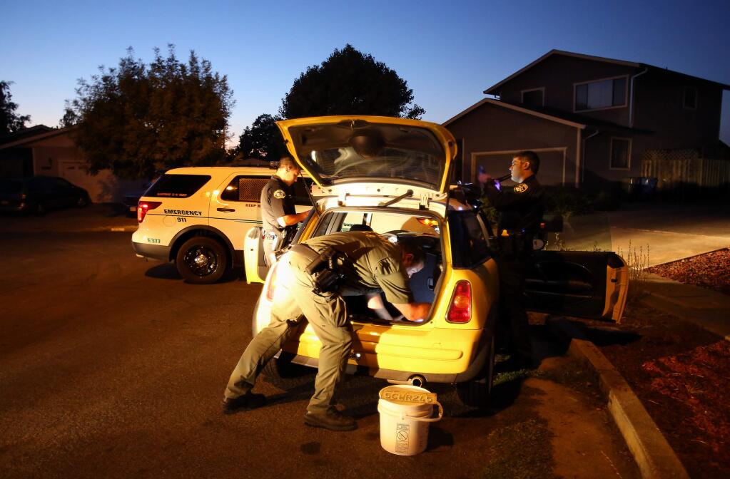 Sonoma County Sheriff's deputies Dylan Fong, left, and Greg Piccinini, and California Highway Patrol Officer Adam Honzell search Joe Carlos Suazo's vehicle, in Santa Rosa on Thursday, August 21, 2014. Suazo had felony warrants and was on Sonoma County's top ten most wanted list at the time of his arrest.(Christopher Chung/ The Press Democrat)