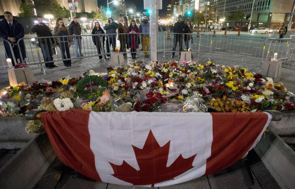 People look at the makeshift memorial near the National War Memorial near Parliament Hill, where Cpl. Nathan Cirillo, 24, was killed by a gunman, Thursday, Oct. 23, 2014 in Ottawa, Ontario. (AP Photo/The Canadian Press, Justin Tang)